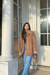 a lady in a brown coat and a pair of jeans